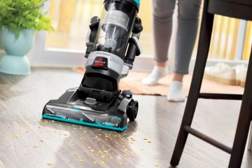 CleanView Rewind Vacuum vacuuming crumbs from hard flooring under chair