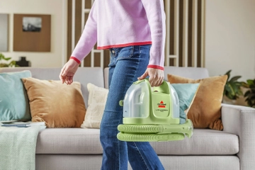 Little Green Mini Portable Carpet Cleaner being carried across living area