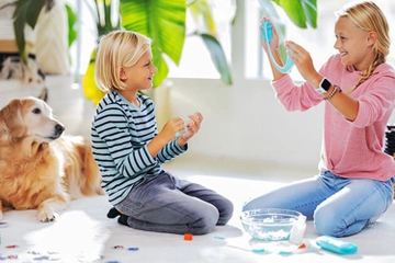 Kids playing with slime over carpet and dog nearby