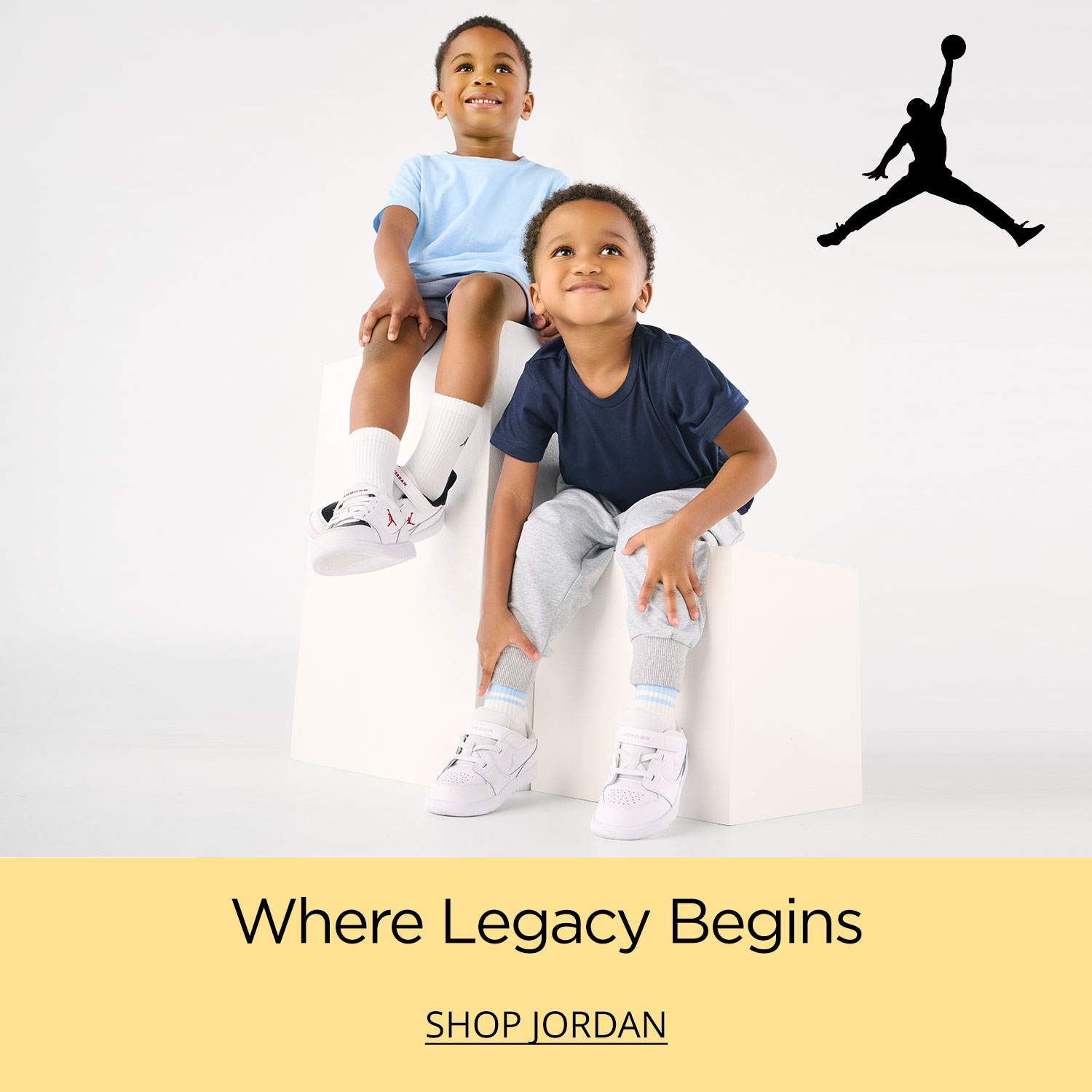 Two young toddler brothers sitting on plinths wearing the latest kids Jordan sneakers.