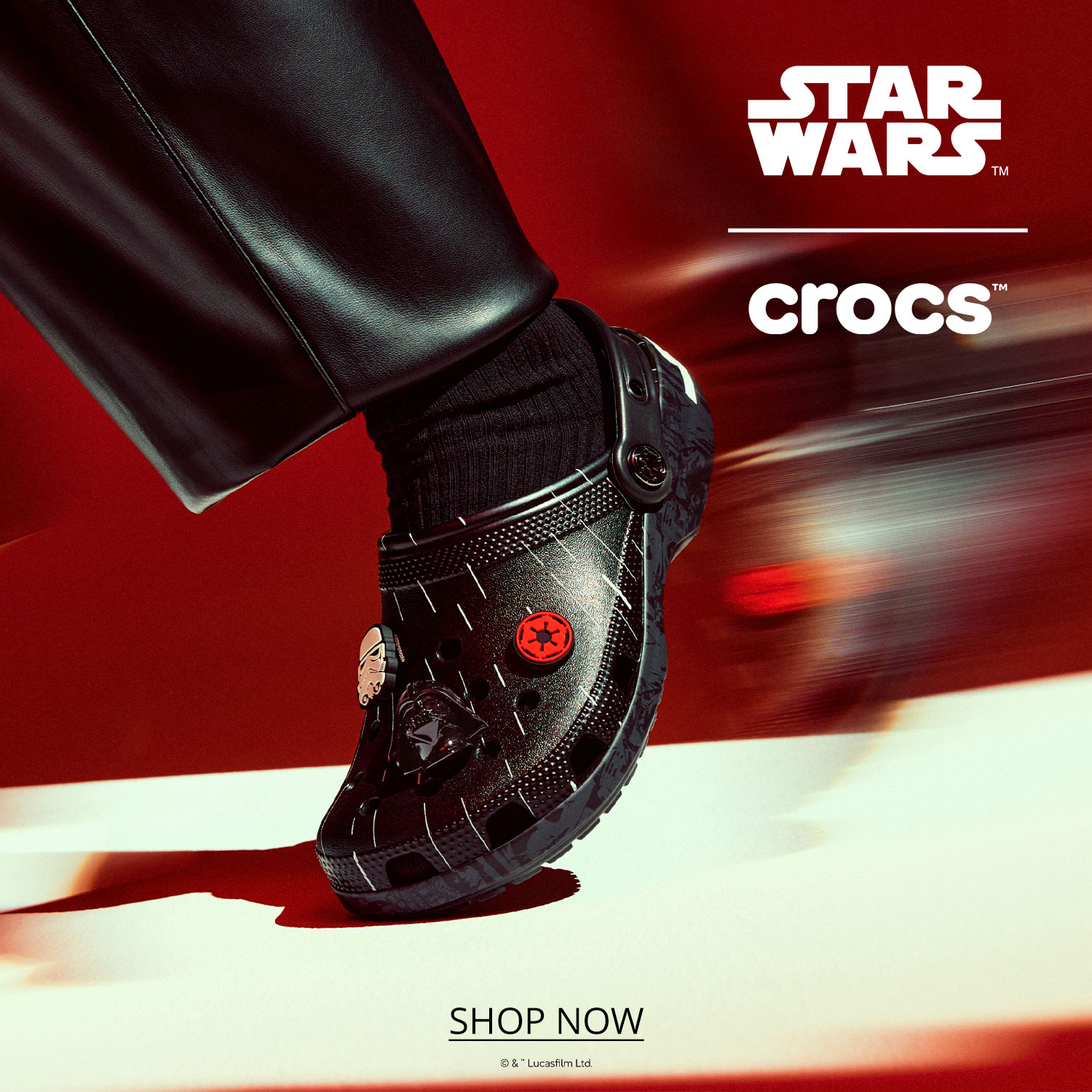 A limited-edition black Star Wars Crocs clog with movie-themed Jibbitz charms, featured against a rushing red background with a fast motion blur effect
