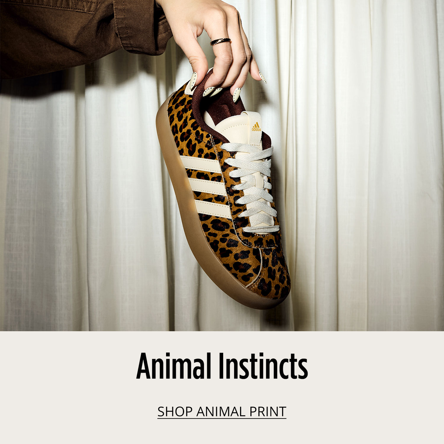 Close-up of adidas animal print sneaker held in woman's hand		