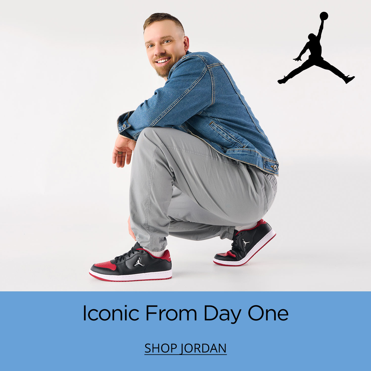 A stylish young dad crouching on the ground wearing his brand new black and red Jordan Court Connect Low Sneakers.	