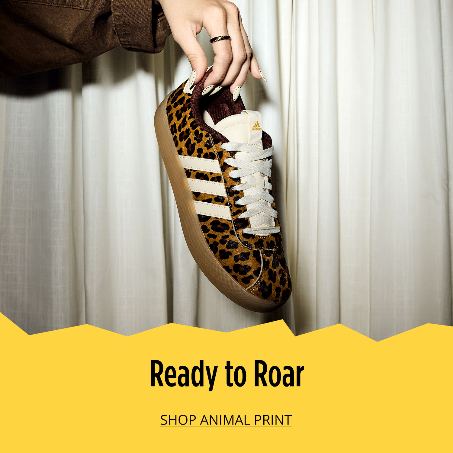 Close-up of adidas animal print sneaker held in woman's hand		