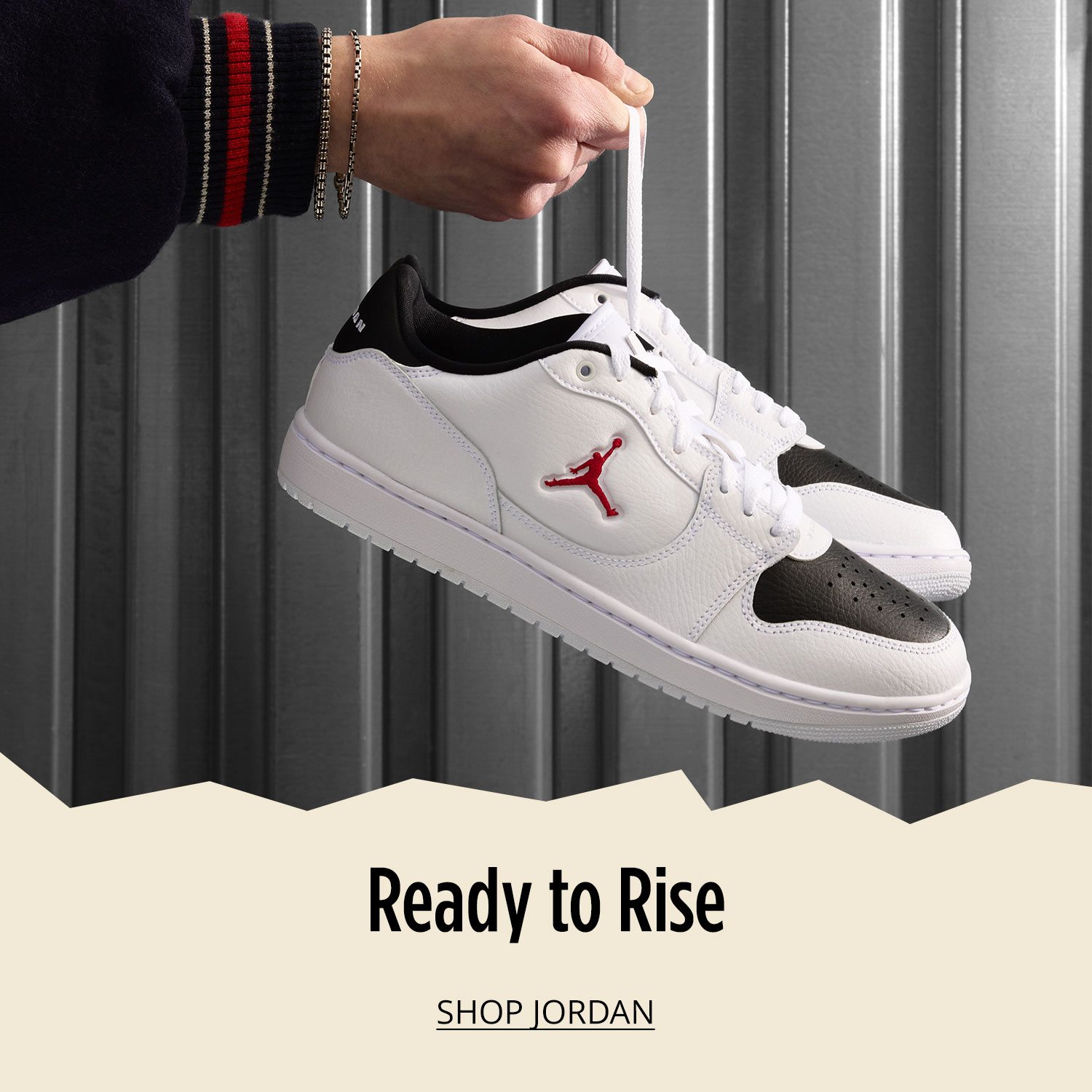 A man's hand holding white pair of Jordan sneakers