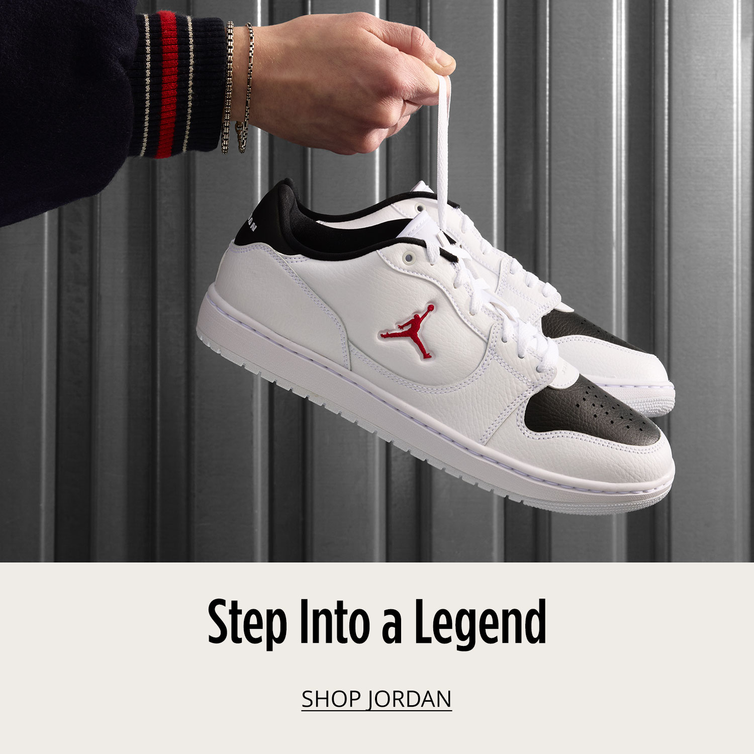 A man's hand holding white pair of Jordan sneakers