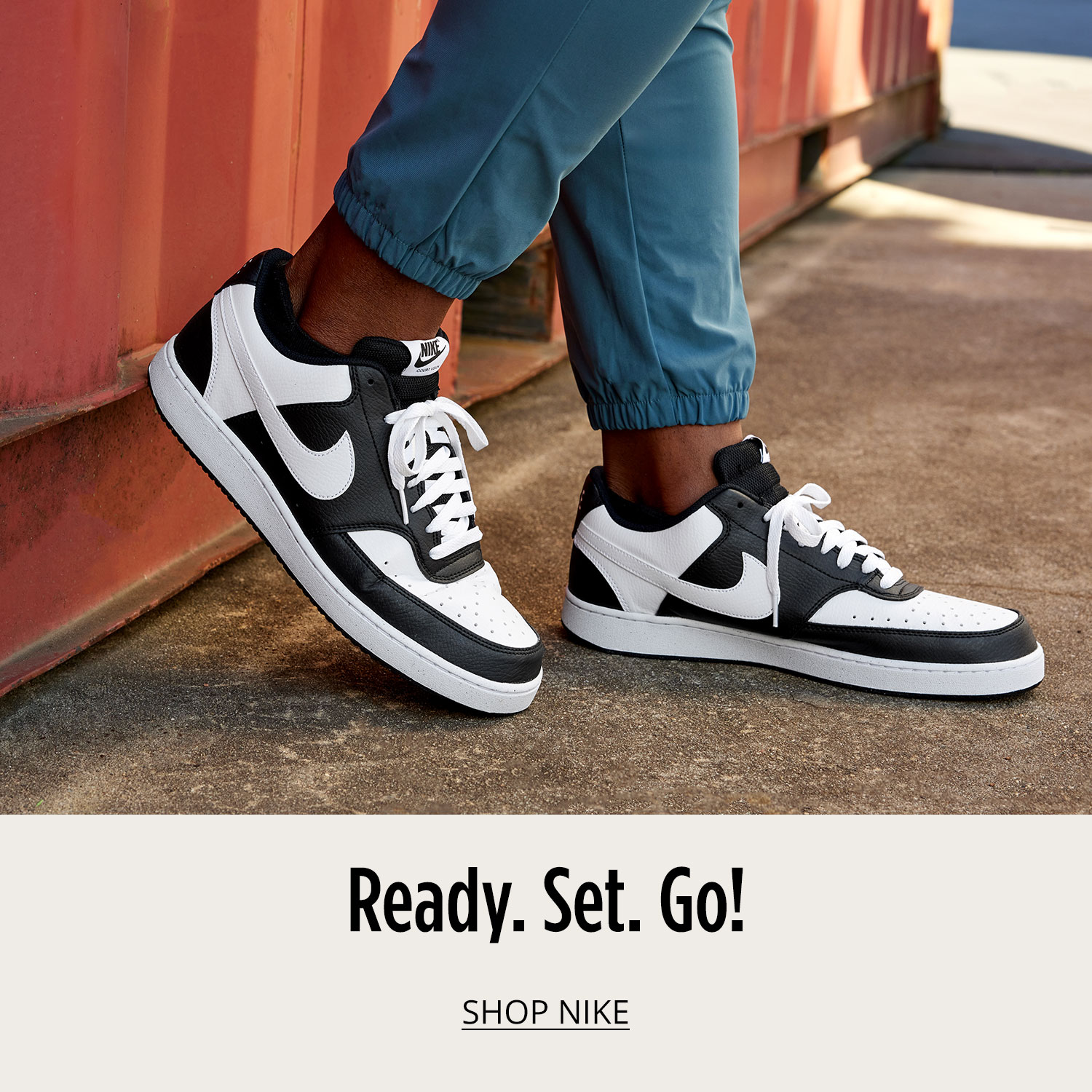 A man wearing black and white pair Nike court sneakers