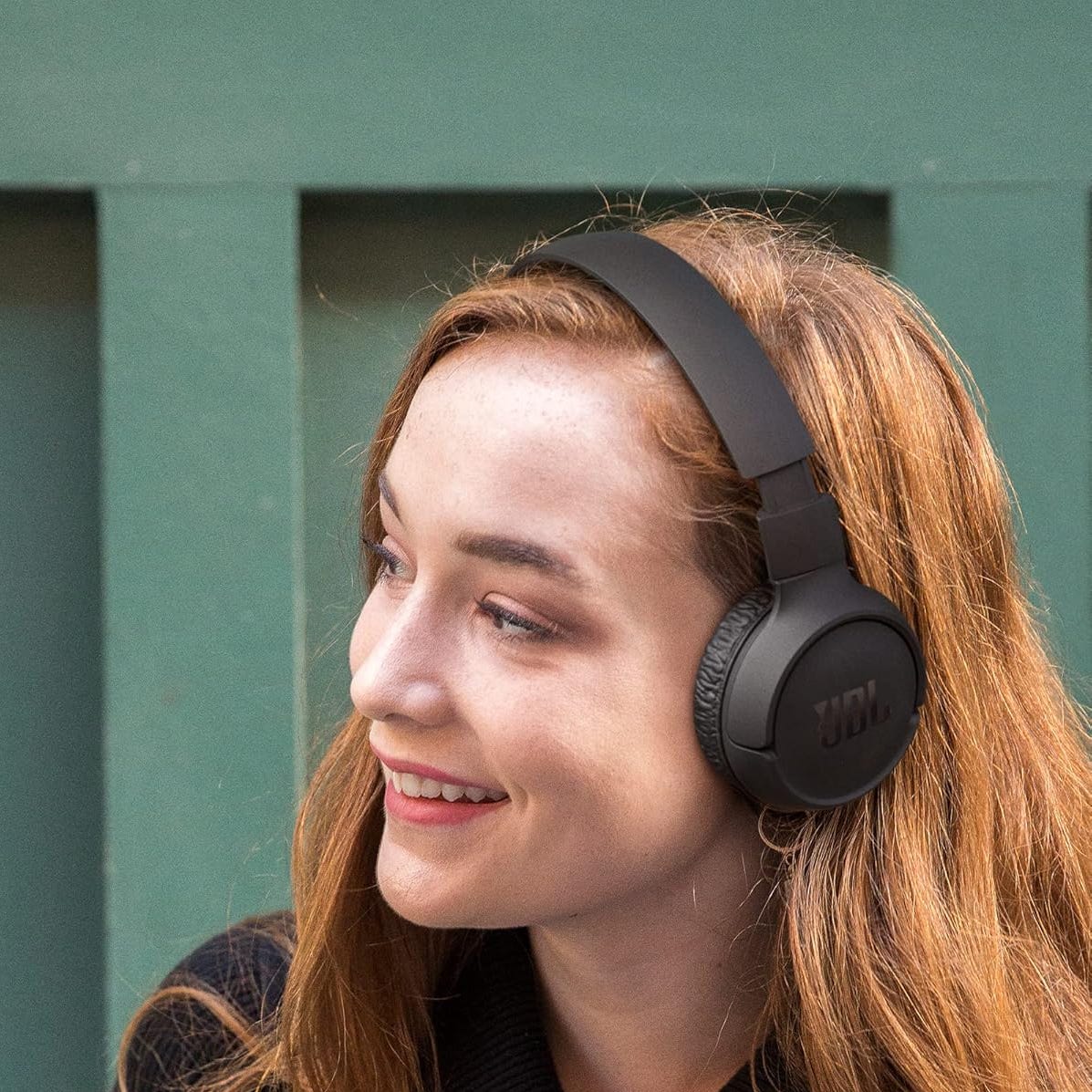 A woman wearing JBL over-ear headphones.