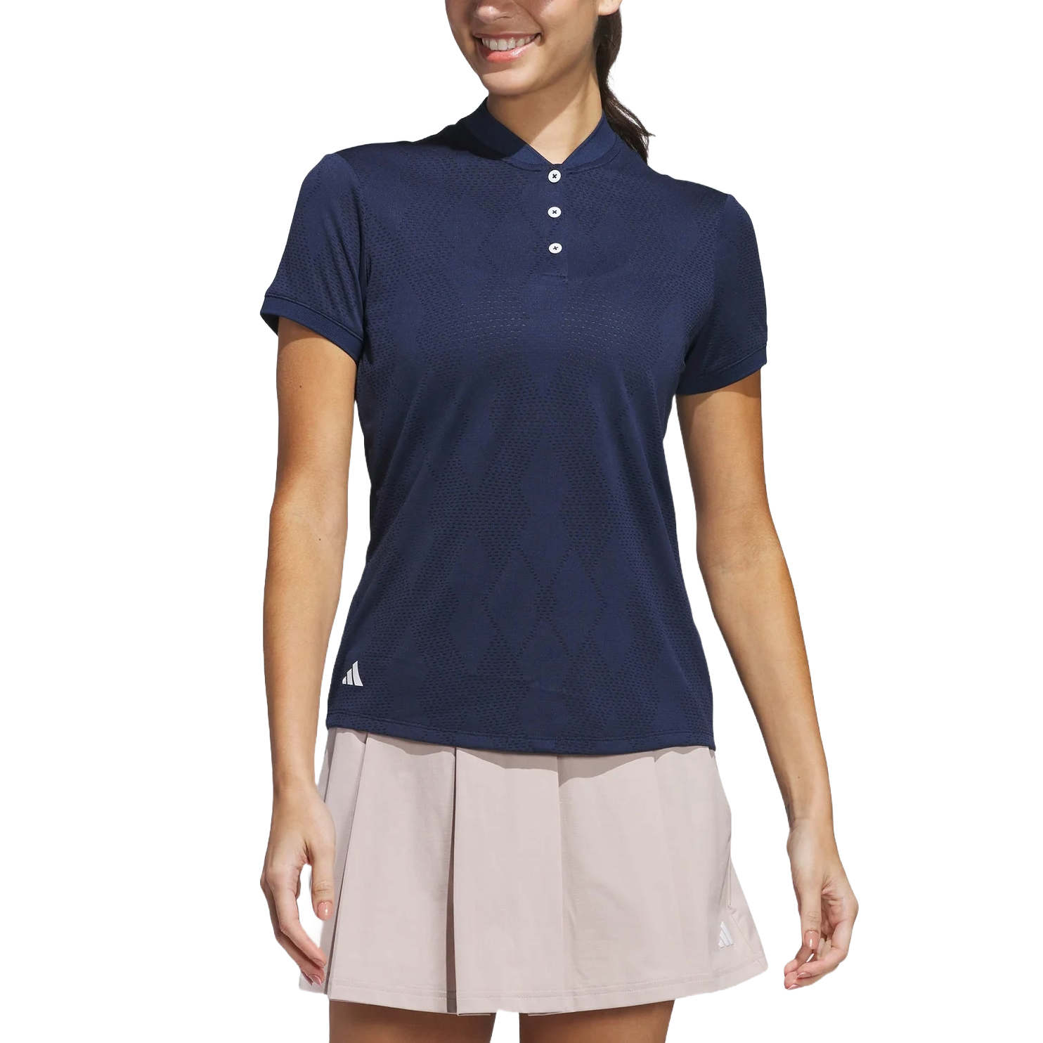 A woman wearing a navy collared polo shirt with a subtle diamond pattern and a light pink pleated skirt, both featuring a minimalist logo.