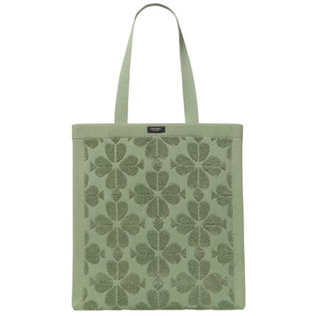 A green tote bag with a floral pattern and a small label near the top.