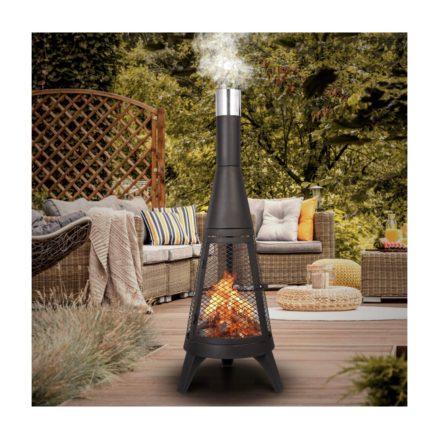 A black outdoor fireplace with visible flames on a patio, surrounded by wicker furniture with cushions and throws.