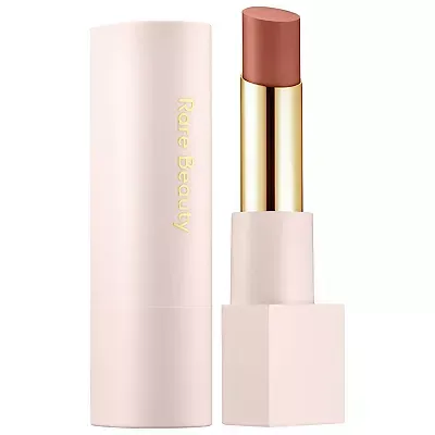 Rare Beauty Dewy Lip Balm with cap removed, showcasing a light brown shade, housed in a matte pink casing with gold accents.