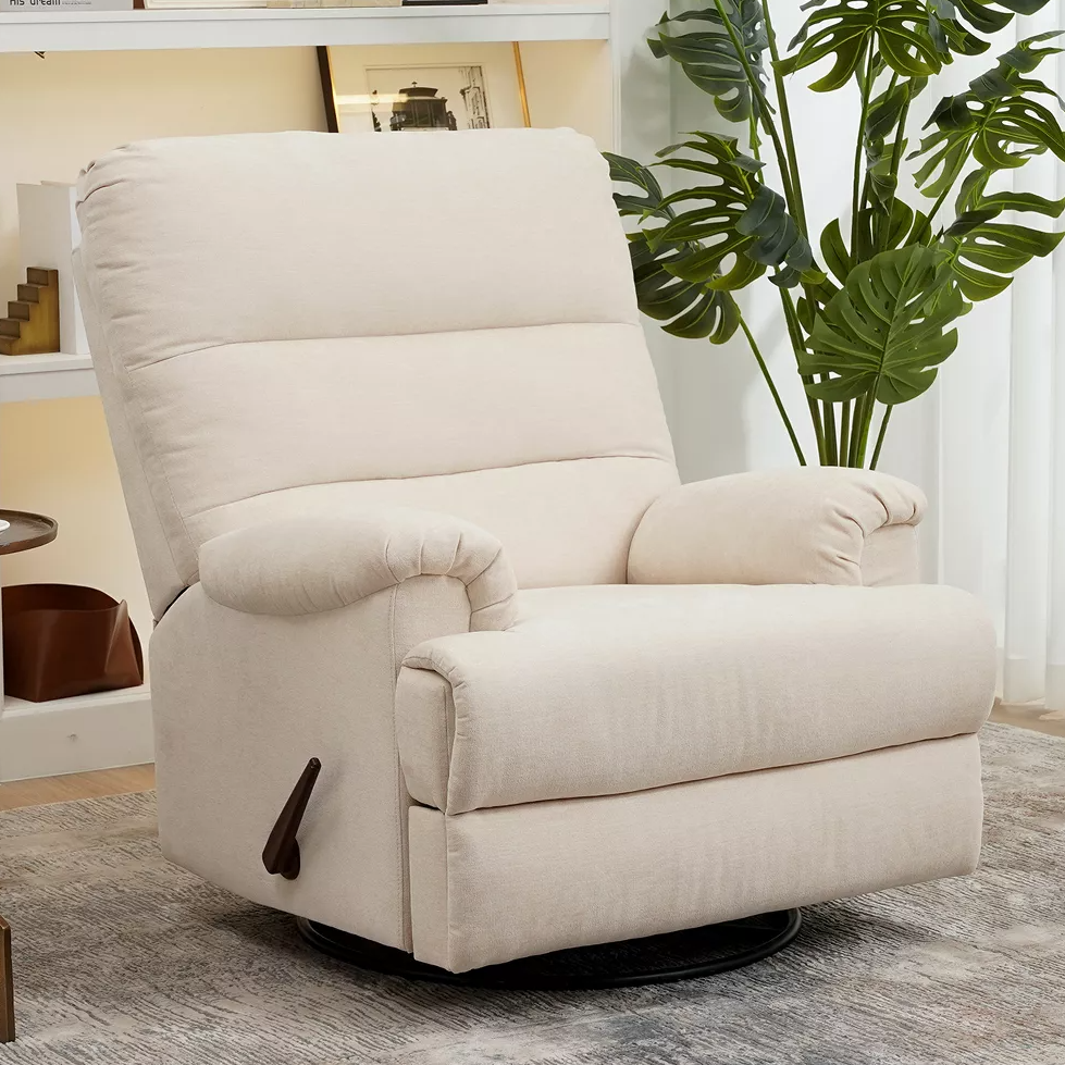 A beige recliner chair with plush cushioning and a manual lever, placed on a patterned rug next to a green plant.