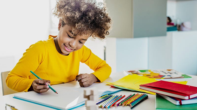 young girl using colored pencils and notebooks