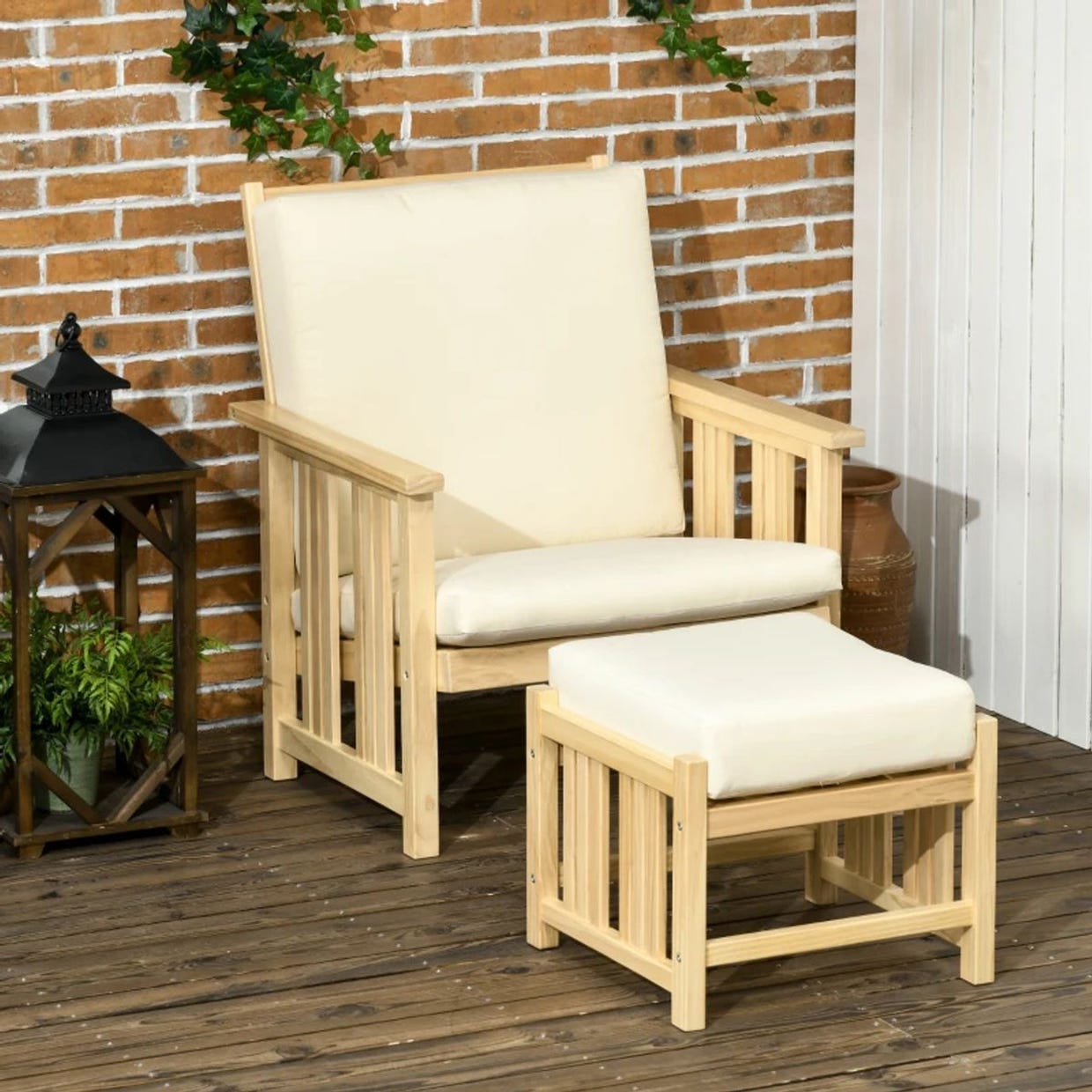 Wooden armchair with an off-white cushion and matching ottoman on a tiled patio floor, against a brick wall backdrop.