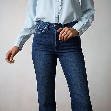 A person is wearing high-waisted jeans in a dark blue wash with a fitted waist and a straight-leg cut. They're paired with a light blue button-up shirt.
