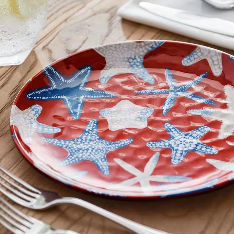 A red and blue starfish-patterned plate on a wooden table, with forks to the side.