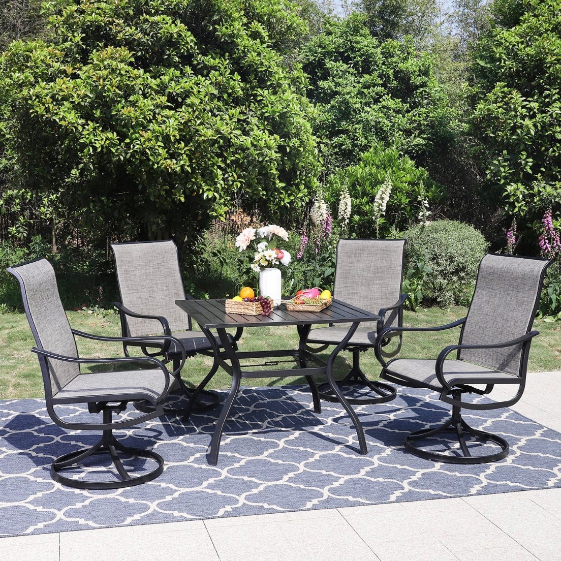 A patio furniture set with four chairs and a rectangular table, displayed outdoors on a patterned rug.