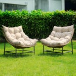 Two plush, beige garden chairs with wicker frames and black metal legs on a lawn.