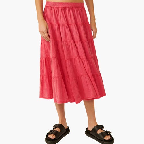 A person wearing a pink tiered midi skirt paired with black sandals.