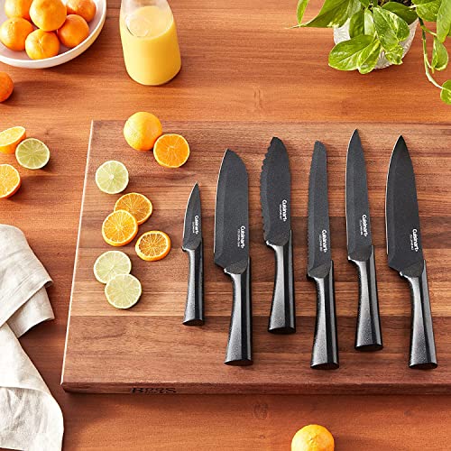 A set of six black Cuisinart knives of varying sizes is displayed on a wooden cutting board amidst citrus fruit slices.