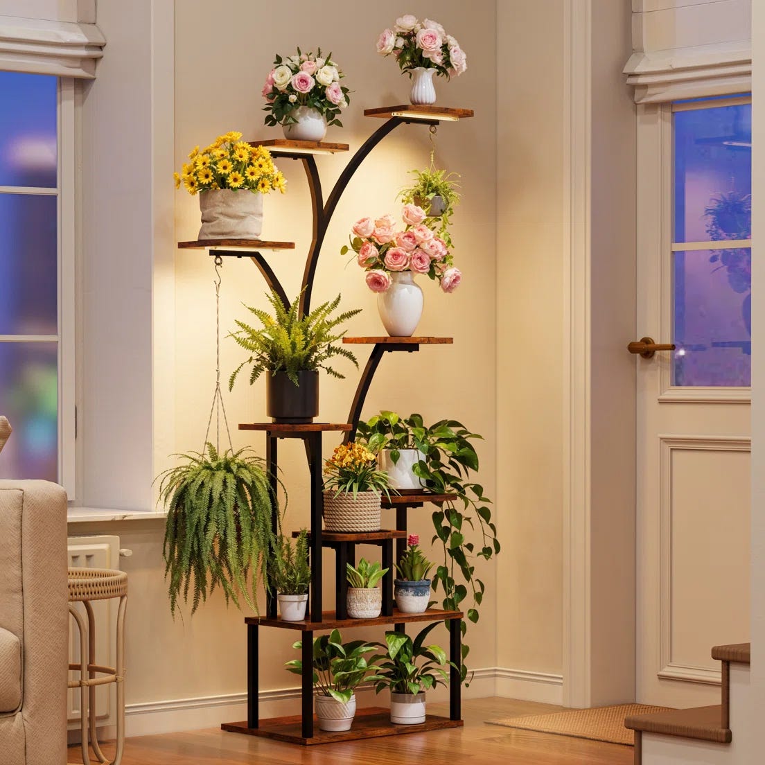 Indoor plant stand with multiple wooden shelves holding various potted plants, including ferns and flowering plants, set against a corner wall in a cozy living space.