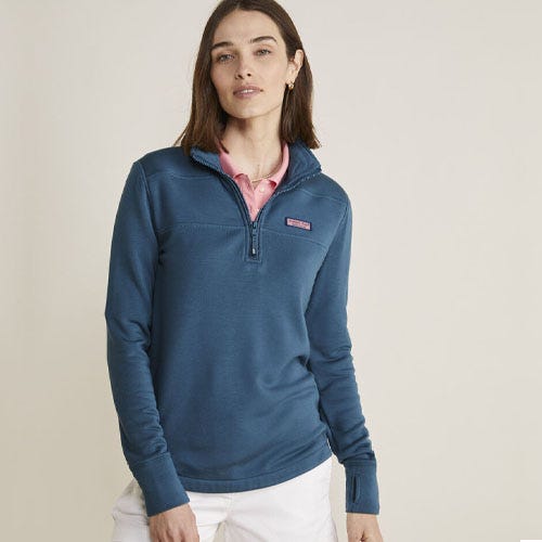 A woman is wearing a teal quarter-zip pullover and a pink shirt underneath.