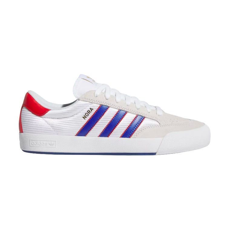 Adidas sneaker featuring a white base, beige suede accents, red and blue stripes, a red heel, and \“NORA\“ text on the side.