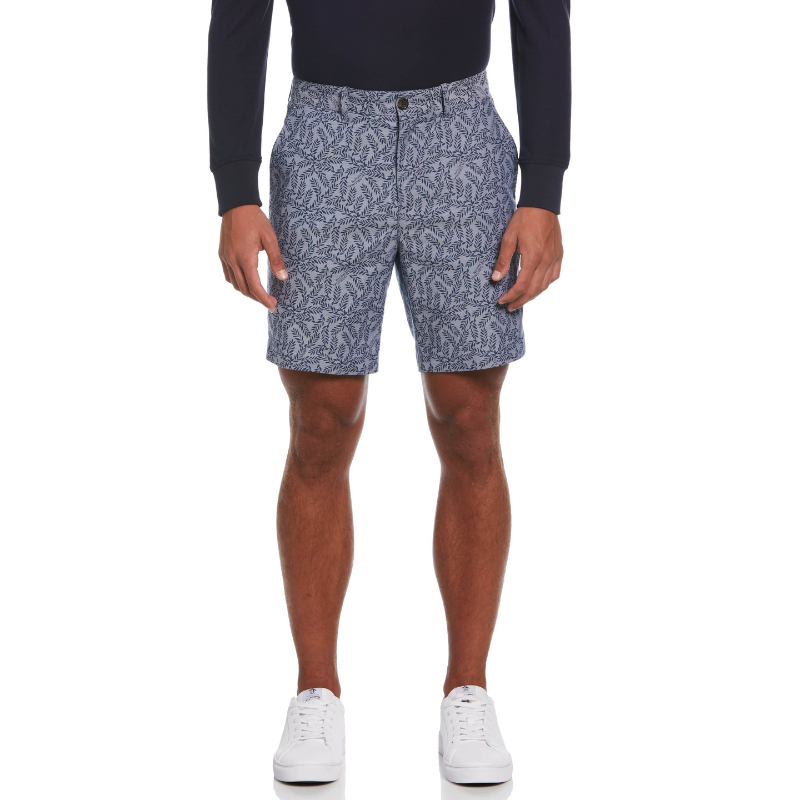 A person is wearing patterned blue shorts with a leaf design, paired with a black long-sleeve shirt and white sneakers.