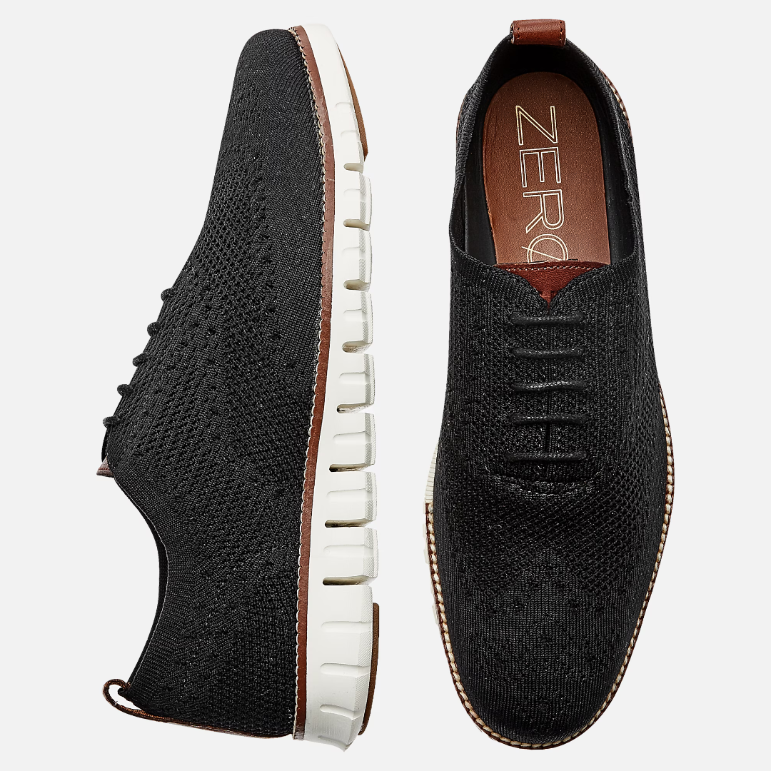 A pair of black knitted sneakers with a white sole and brown insole.