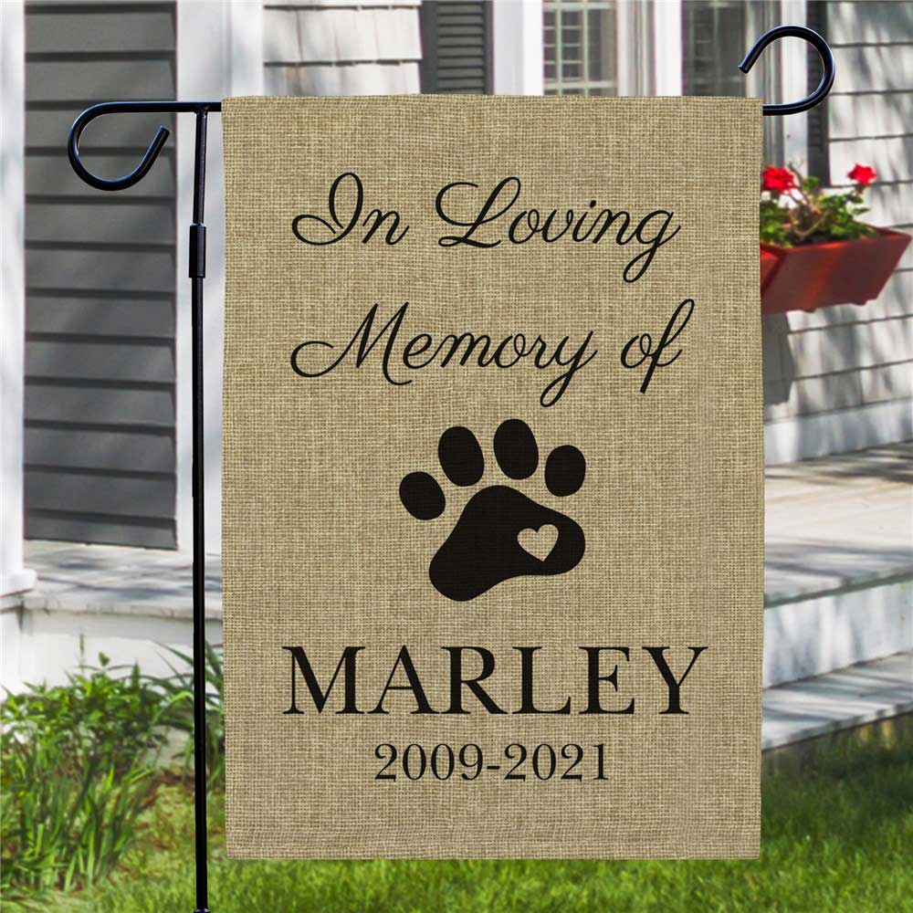 A burlap garden flag commemorates a pet named Marley (2009-2021) with the text \“In Loving Memory of\“ and a paw print design.