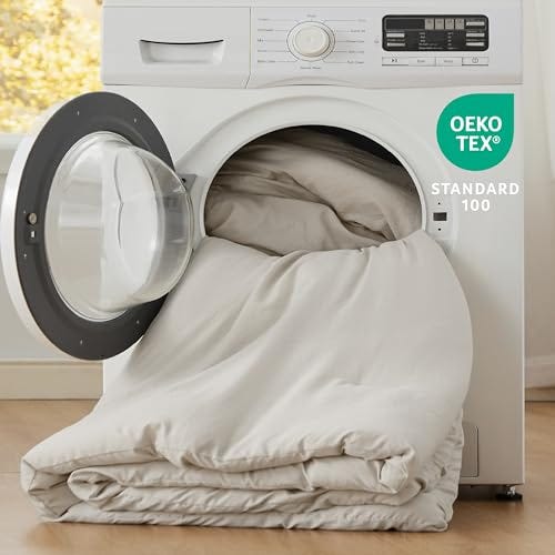 A comforter with a soft-washed texture is partially inside a washing machine, indicating it is machine-washable, and features the OEKO-TEX Standard 100 label.