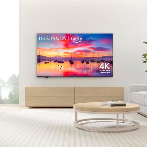 Insignia 50-inch 4K Fire TV mounted on a wall, displaying a vibrant sunset scene with boats.