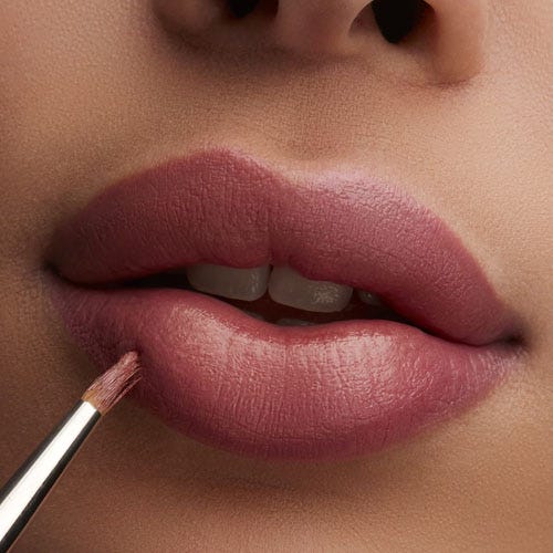 Close-up of lips with matte lipstick being applied with a brush.