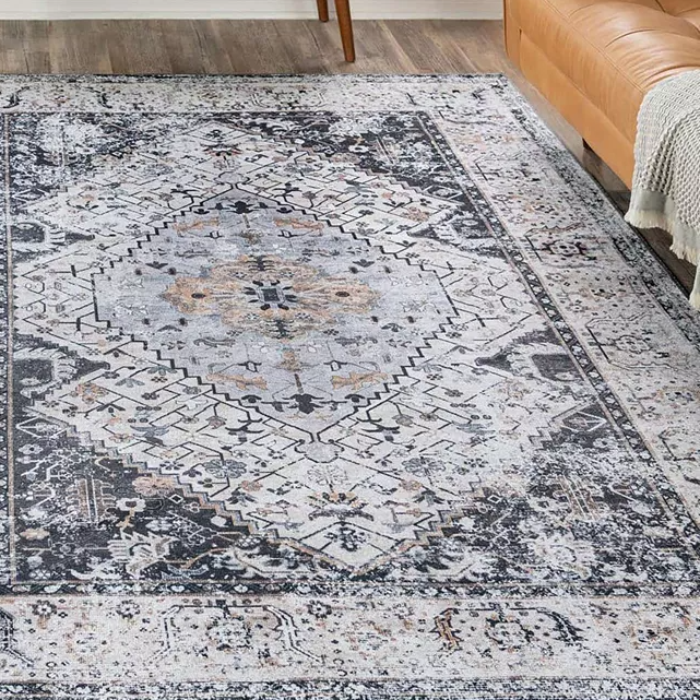 A patterned area rug with a central medallion design in shades of gray, black, and ivory.