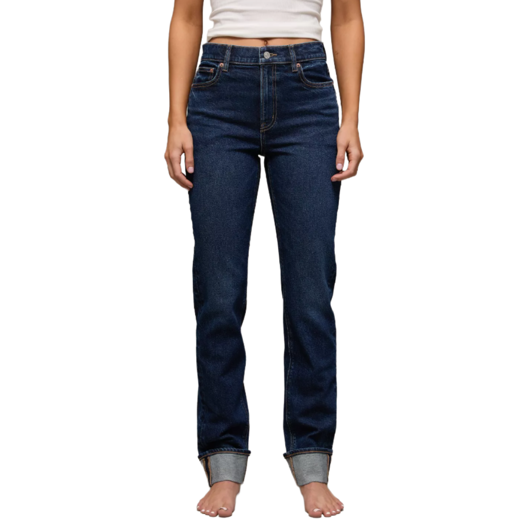 A person wearing dark blue, high-waisted straight-leg jeans with turn-up cuffs, paired with a white sleeveless top.