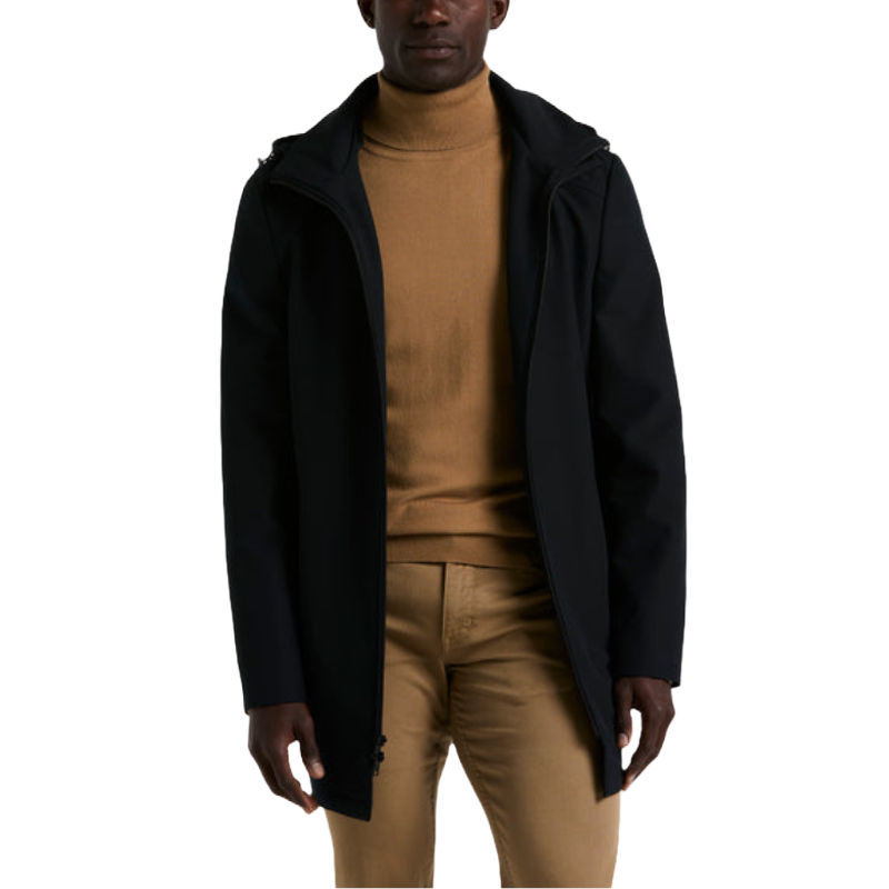 A man is wearing a black coat over a tan turtleneck and tan pants.