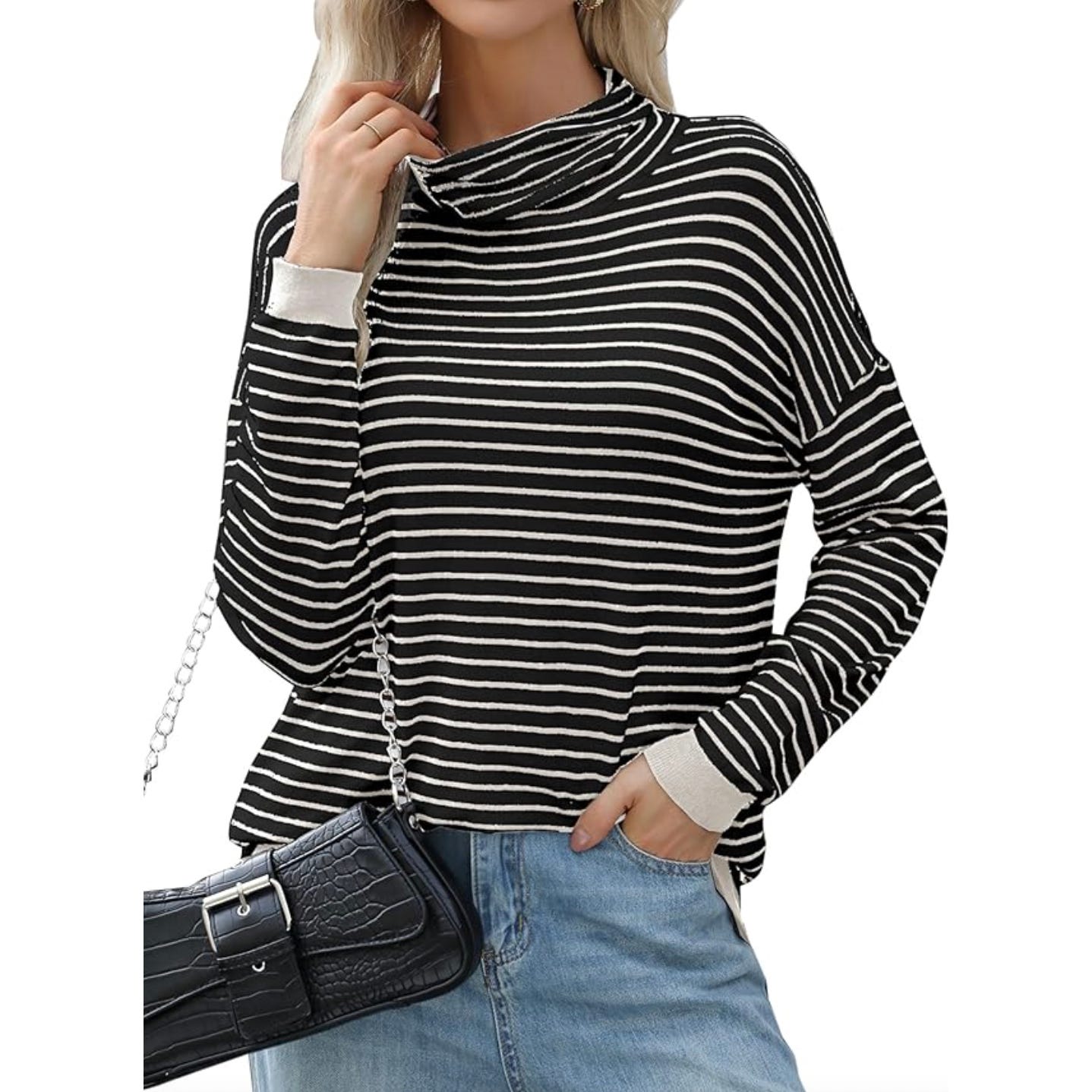 A woman is wearing a black and white striped turtleneck sweater with long sleeves, paired with light blue jeans. She carries a black crocodile-textured handbag with a chain strap.