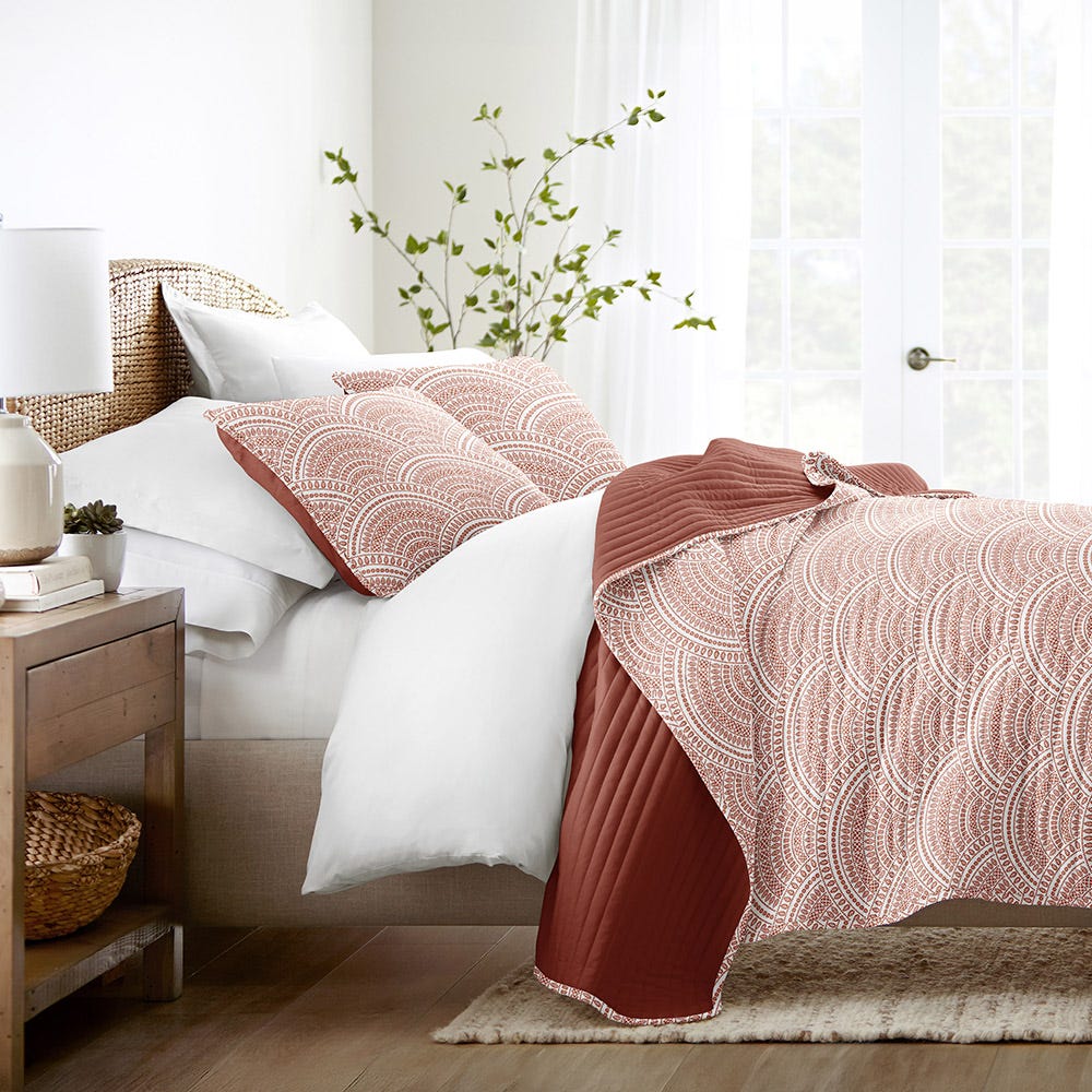 Bedding set with patterned comforter, pillows, and white sheets.