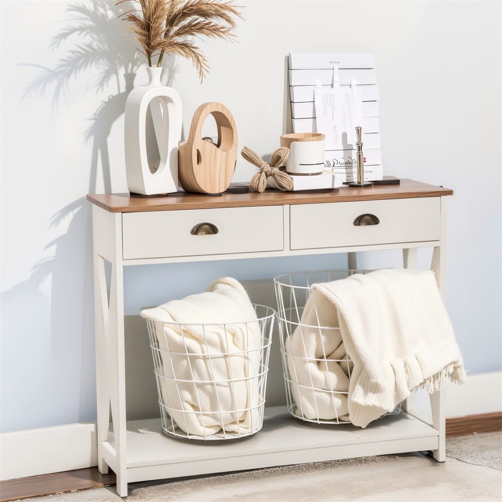White console table with a wooden top, featuring decorative vases, a plant, and organizers on top. Below are two wire baskets holding cream-colored blankets.