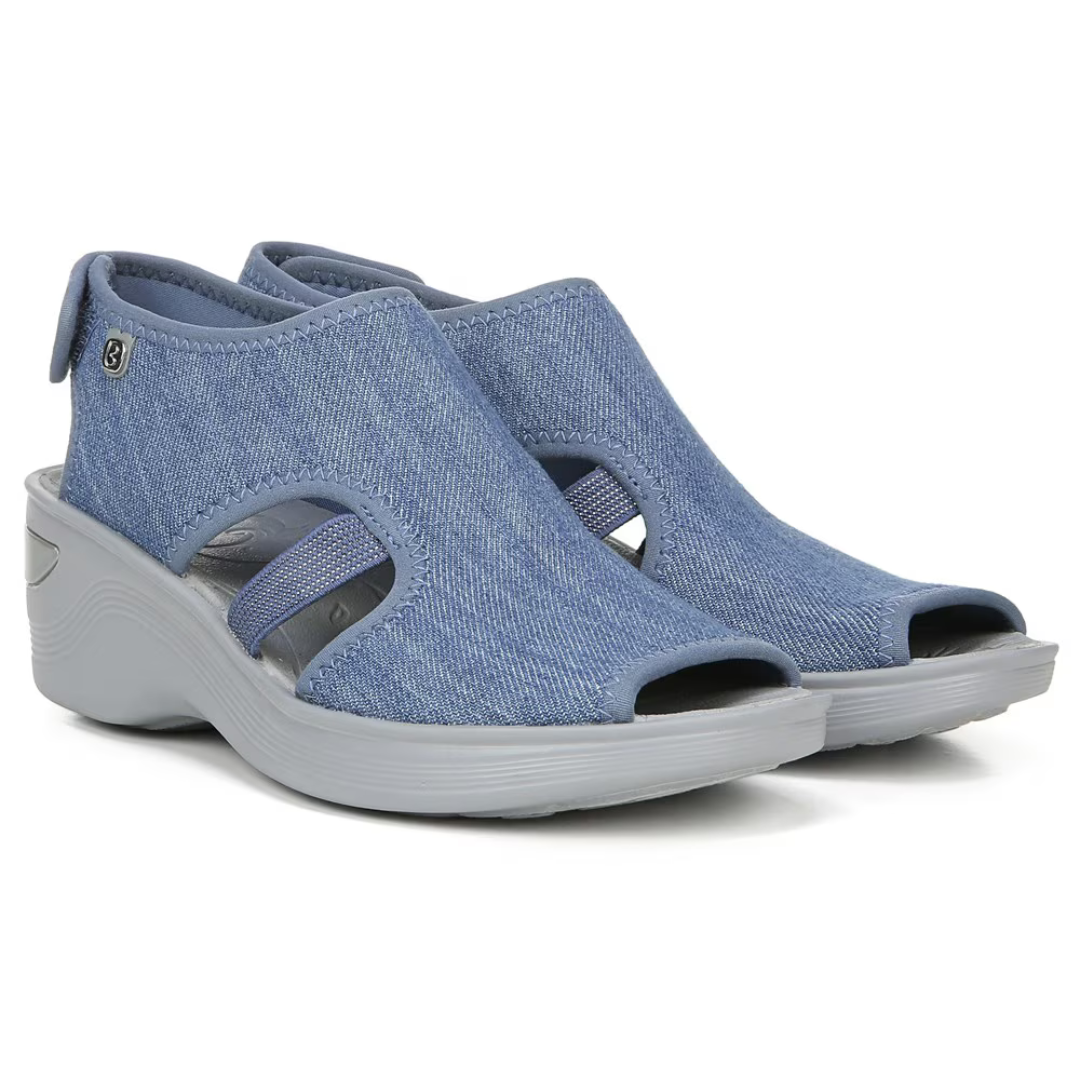 Blue wedge sandals featuring a stretch fabric upper with an open toe and cut-out design, complemented by a sporty white sole.