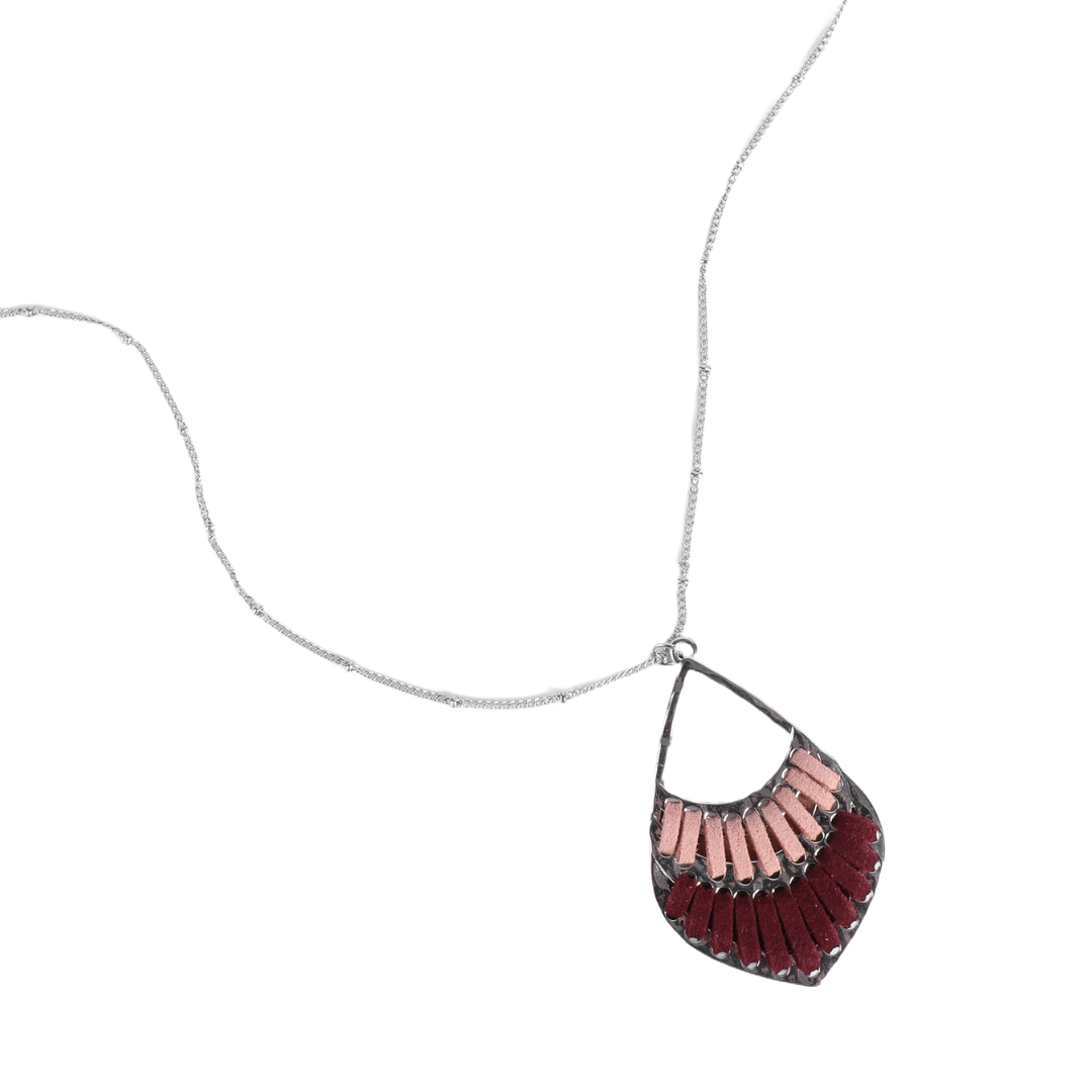 A necklace featuring a teardrop-shaped pendant with a pattern of alternating dark red and light pink segments, hanging from a silver chain.