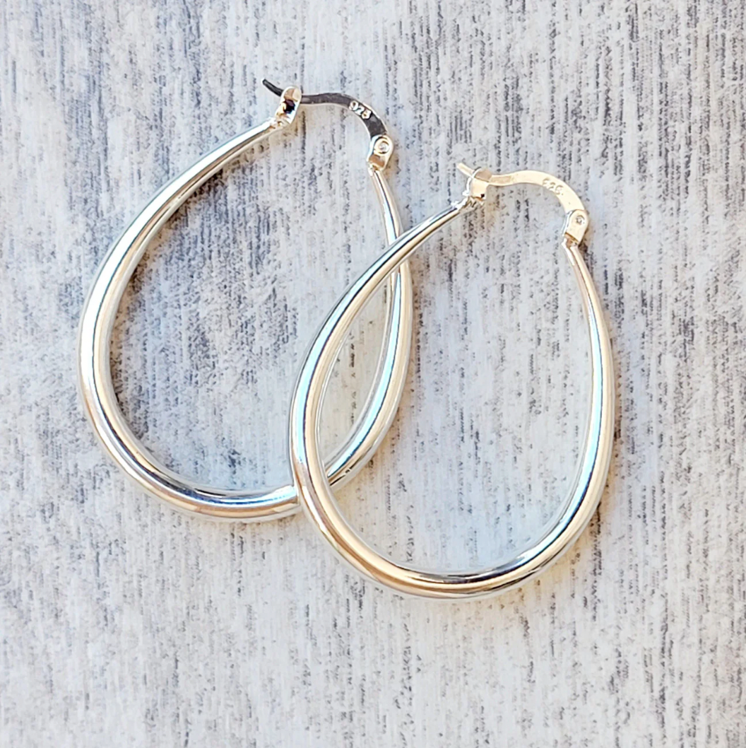 Silver hoop earrings with a teardrop shape, featuring a smooth, polished finish and a clasp closure. Stamped \“925\“ indicating sterling silver.