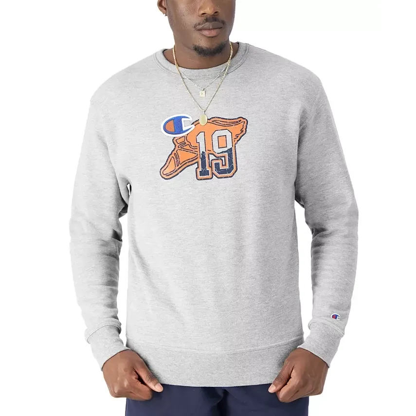 A man wearing a gray crewneck sweatshirt with a large sports team logo and the number 19 on it.