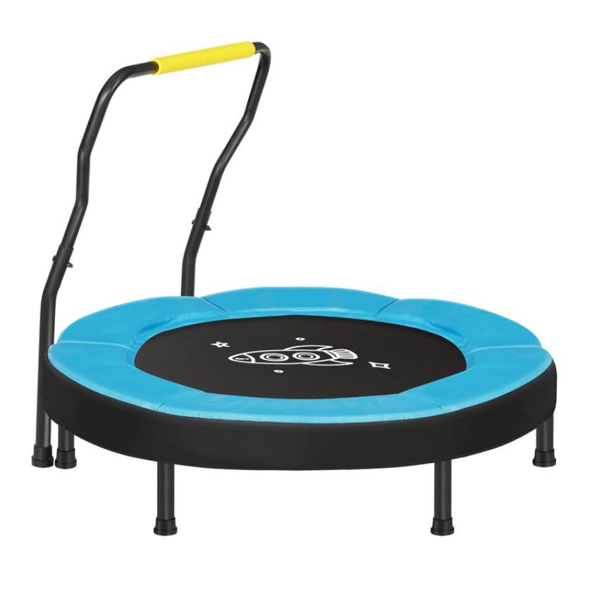 A small trampoline with a blue padded rim, featuring six legs for stability and a black jumping surface with a rocket design. It has a safety handlebar with a yellow grip.