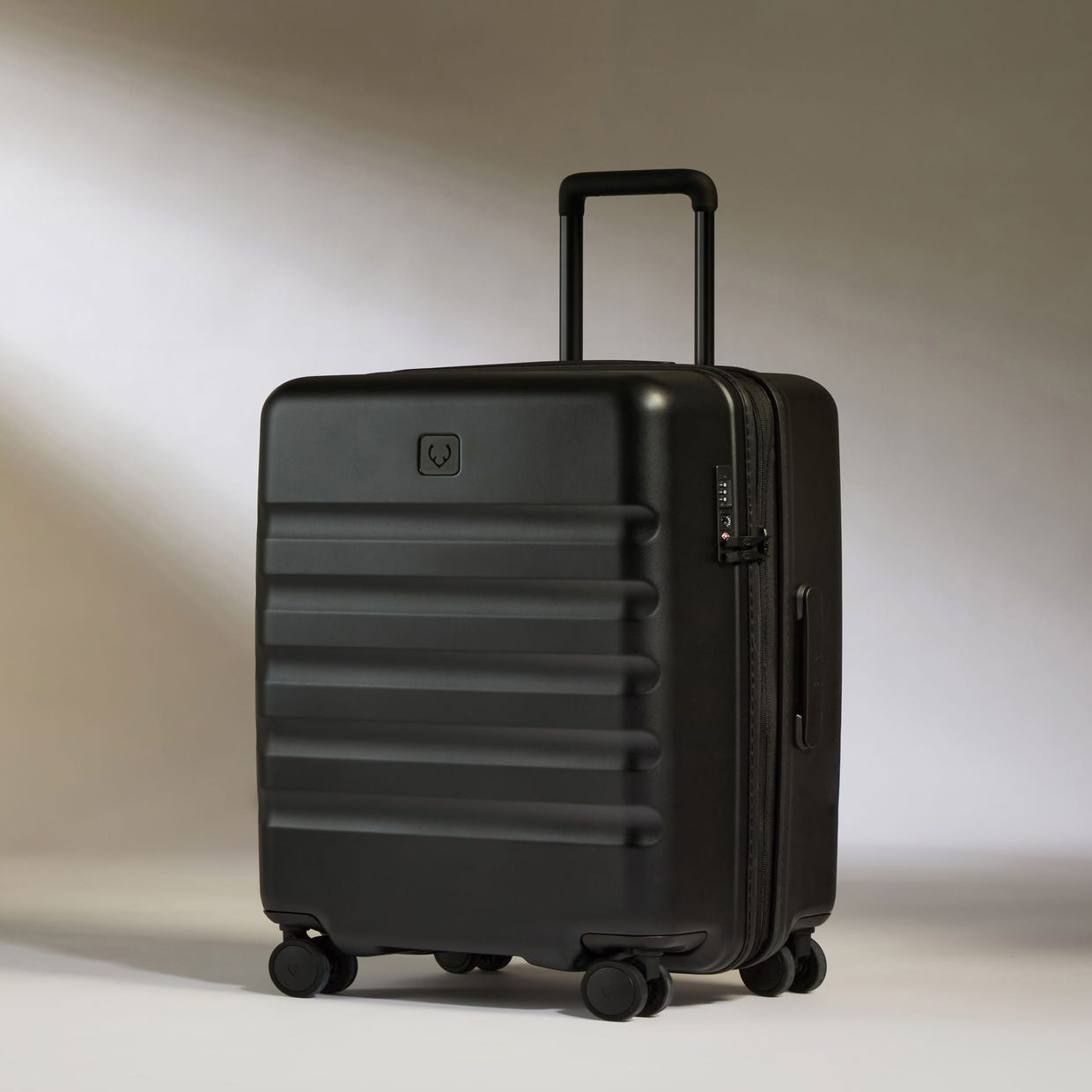 A black Antler Luggage Icon Stripe Spinner with horizontal ridges, a retractable handle, and four wheels.
