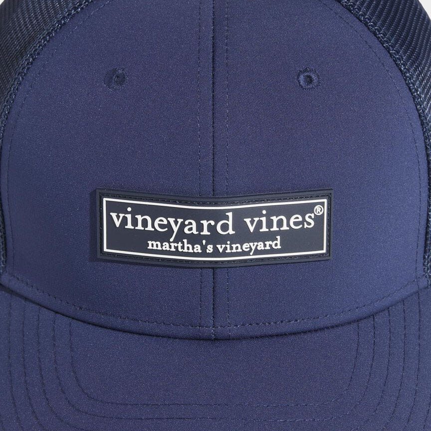 Navy blue Vineyard Vines trucker hat with a black and white logo patch that reads \“vineyard vines martha's vineyard\“ on the front panel. The hat features a breathable mesh back.