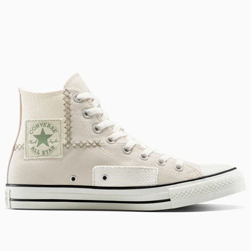 Converse Chuck Taylor All Star high-top sneaker in off-white with a green logo patch, featuring unique stitching and patchwork details.