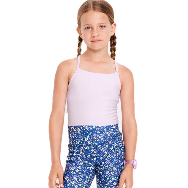 A young girl is wearing a light purple spaghetti strap tank top and blue floral leggings, complemented by a purple watch.