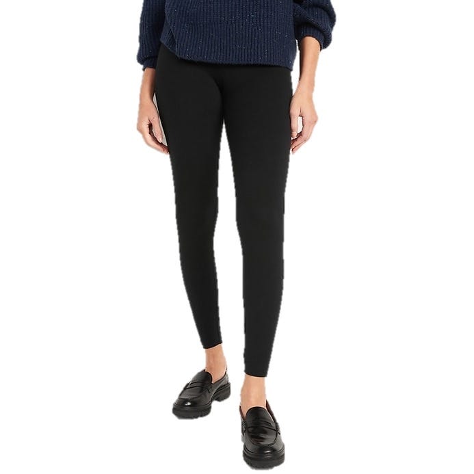 A person wears black leggings paired with black loafers and a navy blue sweater.